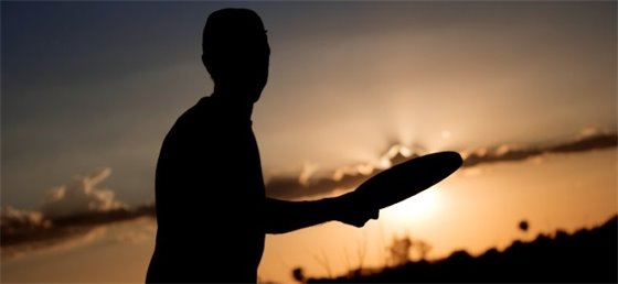 Silhouette of a adult playing frisbee