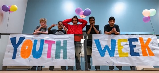Youth standing with a Youth Week banner