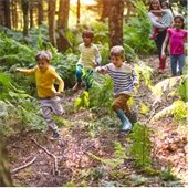 A group of children running on a trail in the forest