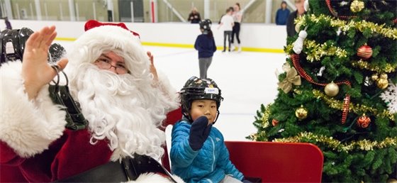 Child posing for a picture with Santa on a sled on ice.