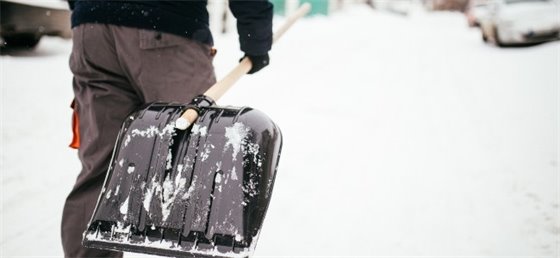 Adult carrying snow shovel