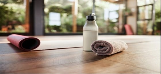 Towel and water bottle resting next to yoga mat.