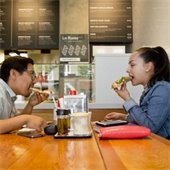 A young woman and man dig into pizza at a restaurant