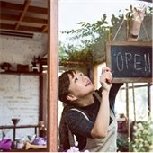 Woman displays an open sign in the window of her shop