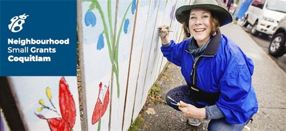 Grant recipient painting a mural on white picket fence.