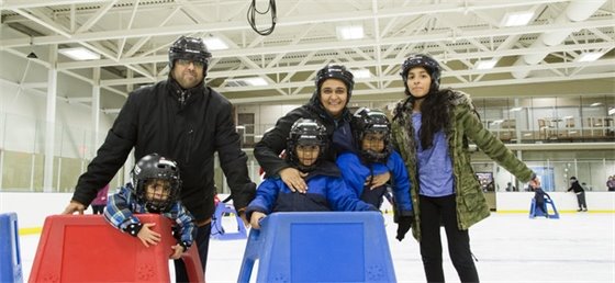Family of six posing for a picture while skating on ice at Poirier Arena.