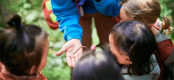 Program Leader holding a worm for kids to observe