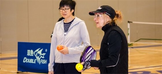 Two adults playing pickeball