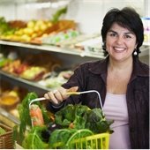 Woman holds shopping basket full of groceries