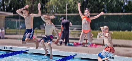 Kids jumping into an outdoor pool