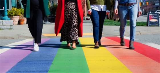 Four people walking on rainbow sidewalk