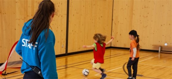 Two young kids playing soccer in Coquitlam facility.