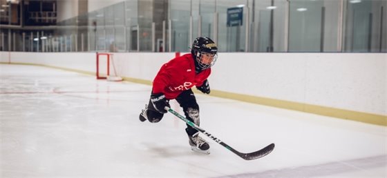 Child skating and holding a hockey stick