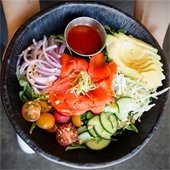 Person holding a black plate of sashimi and sushi 