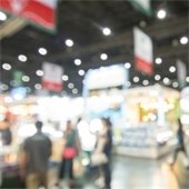Crowd browsing booths at tradeshow, out of focus