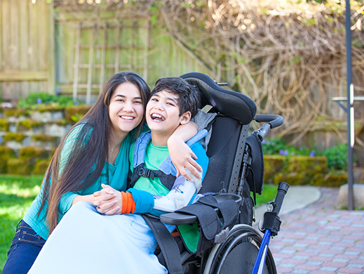 A photo of a woman with her arm around a child in a wheelchair