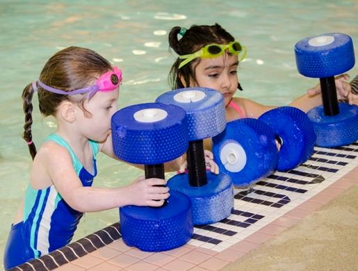 Two children play with floatation devices in swimming lessons