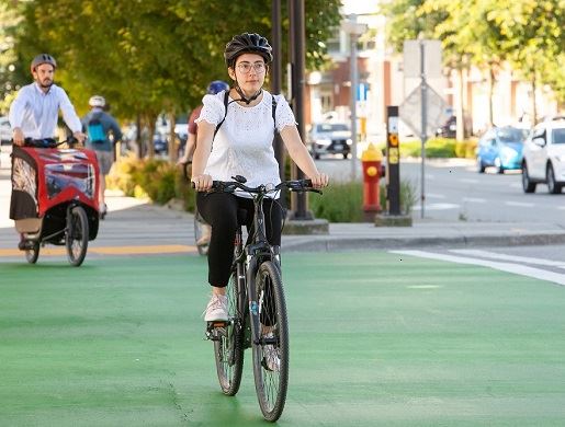 Cyclists wearing helmets on bikes crossing a marked multi-use pathway intersection