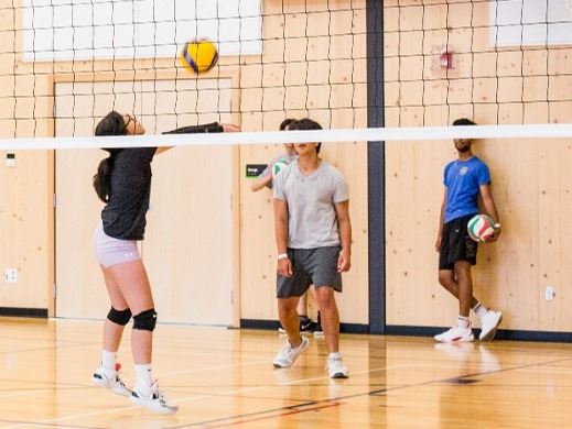 Youth playing volleyball in an indoor gym
