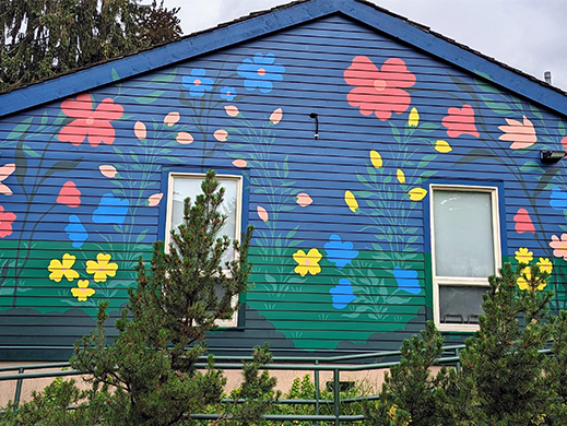 A photo of the mural that is complete at Place des Arts. It is a flowery scene with lots of colour. 