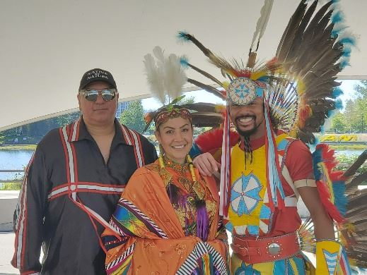 Three Indigenous people, two dressed in 'fancy' traditional costumes