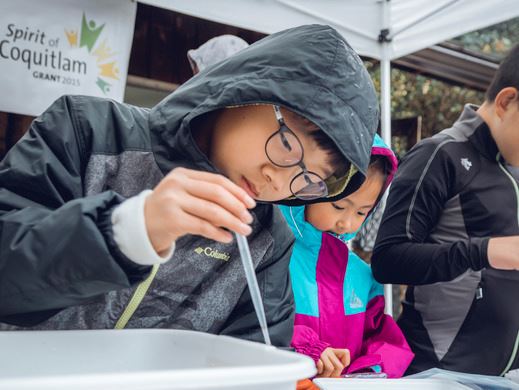A child is experimenting with water samples at an event supported by the Spirit of Coquitlam grant