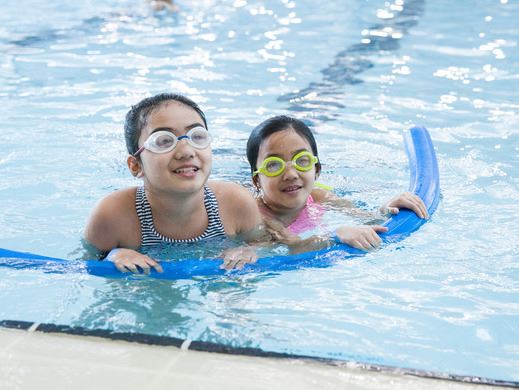 Two girls float in the pool on a noodle