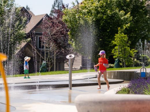 Two young kids splashing in Sheffield Spray Park