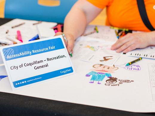 Person coloring at desk with Accessibility and Resource Fair sign