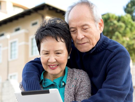 Two seniors with housing in the background.
