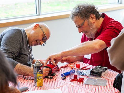 Two adults working on an item repair together 