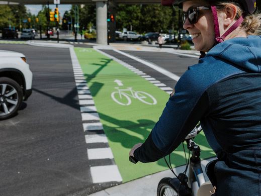 Cyclist wearing their helmet and waiting with their bike at the marked cyclist intersection
