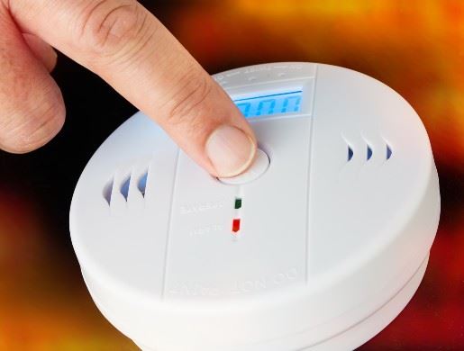 Finger pressing button on smoke alarm