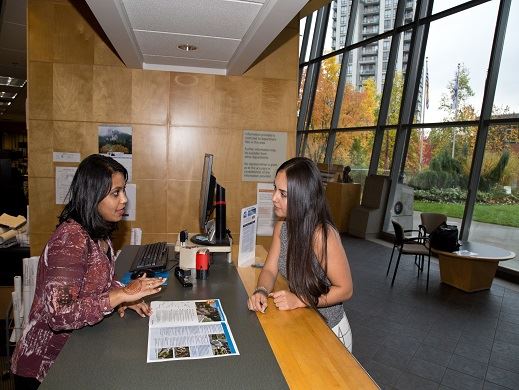 Two women discuss and review a planning brochure at the City of Coquitlam