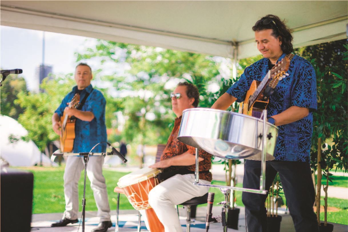 Three musicians play on an outdoor stage at community event