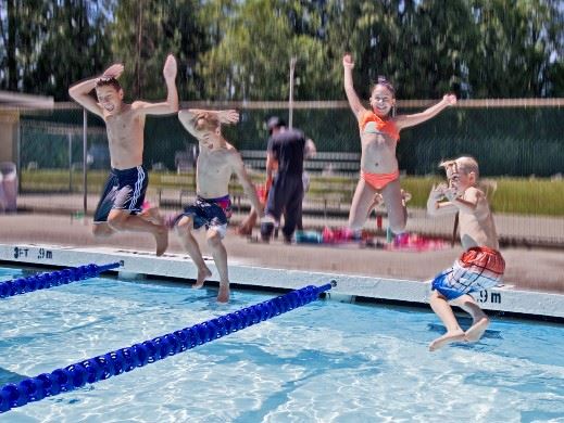 Kids jumping into an outdoor pool