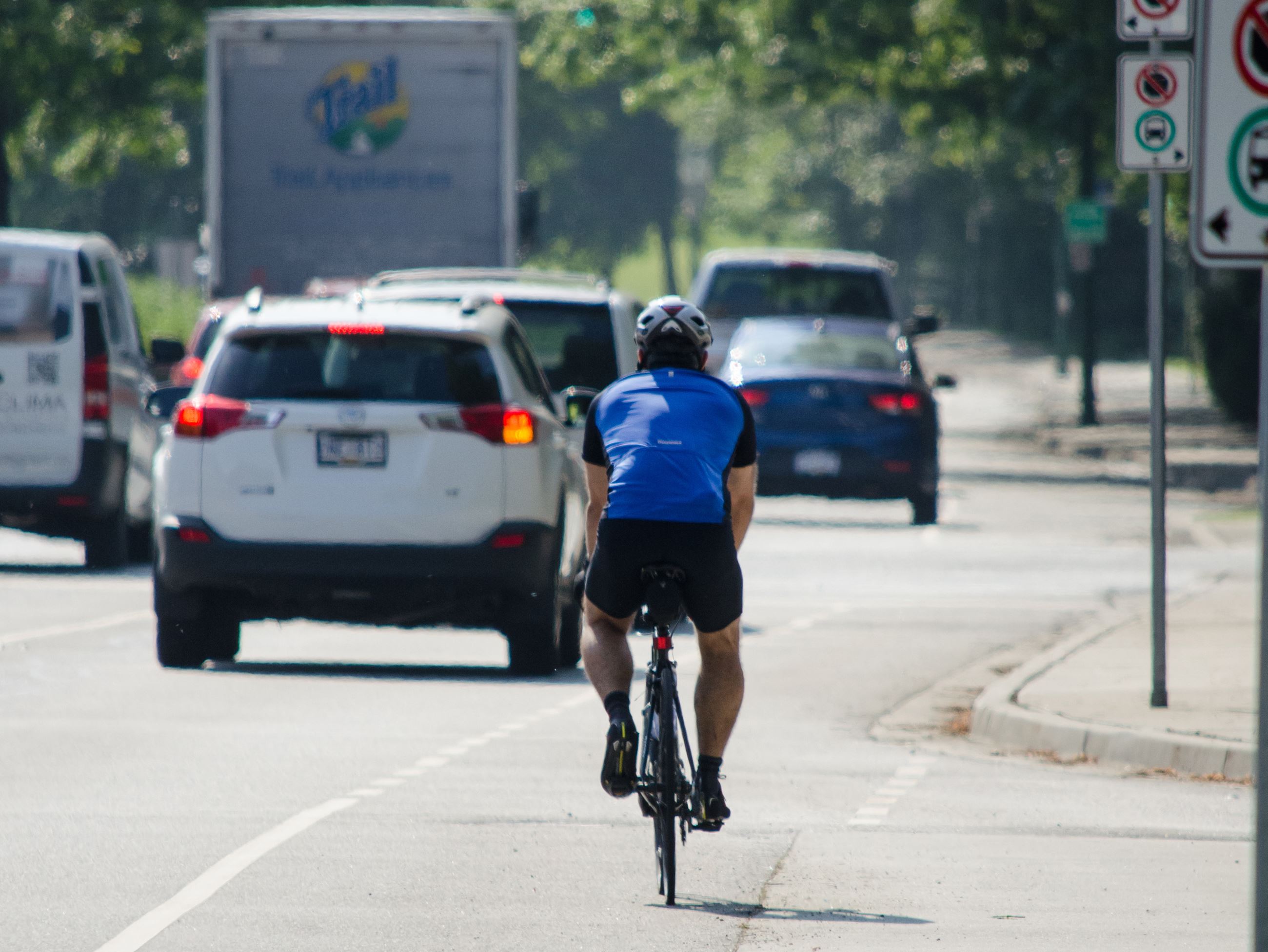 A cyclist rides on a busy street next to cars and trucks