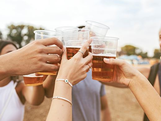 Hands raising a cup of beer to cheers