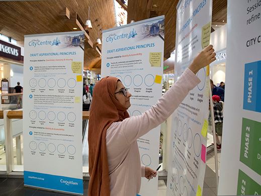 A woman in hijab adds a note to a poster board