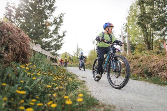 Four kids riding bikes on a gravel park path