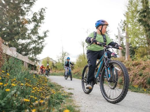 Children riding bicycles outside on a gravel trail