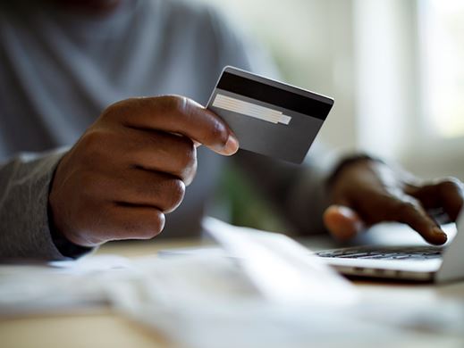 Hand holds a credit card hovering over a keyboard