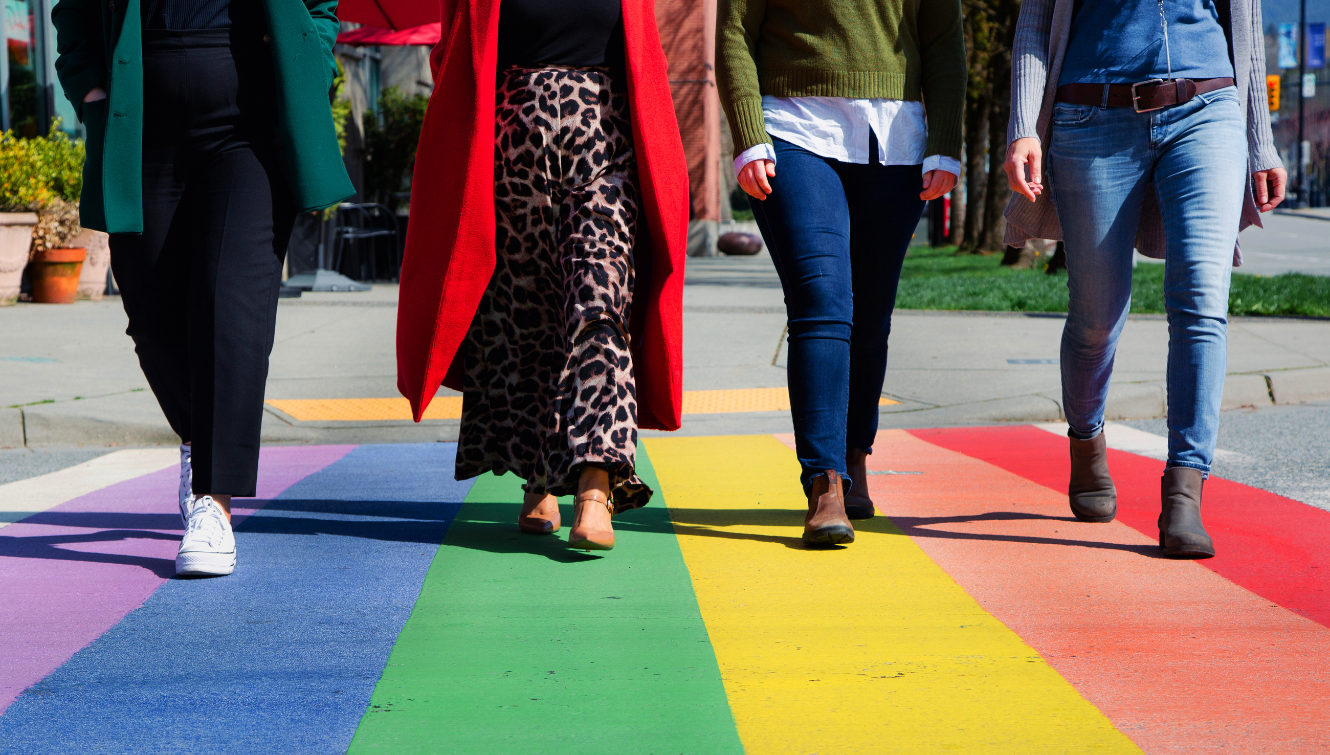Four people walking across the rainbow crosswalk at City Hall in Coquitlam