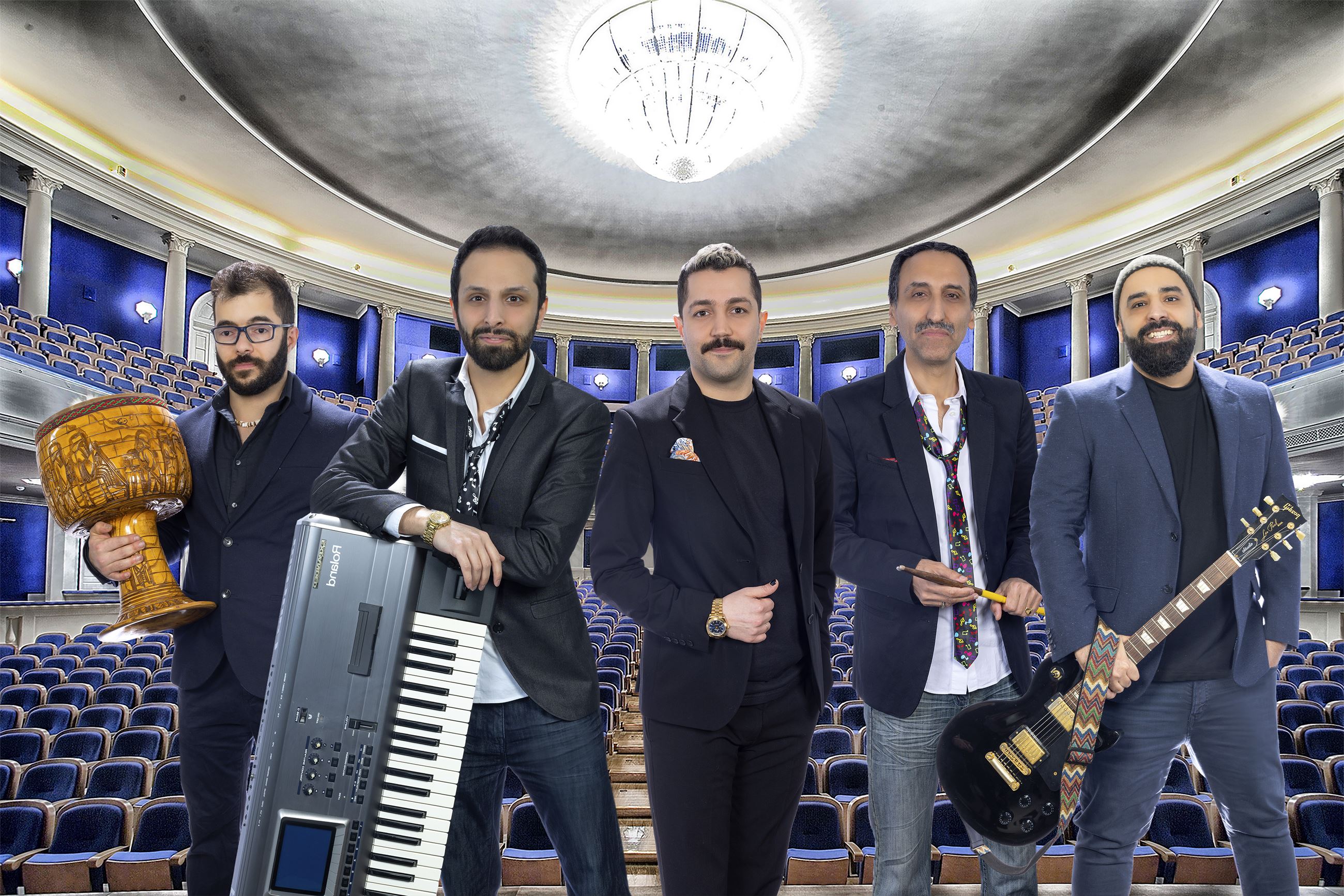 all 5 band members dressed in suits standing on a stage in a concert hall holding their instruments