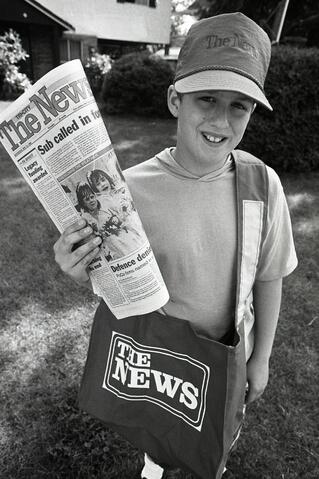Eric Dlugos posing with bag and paper on his paper route, 1988